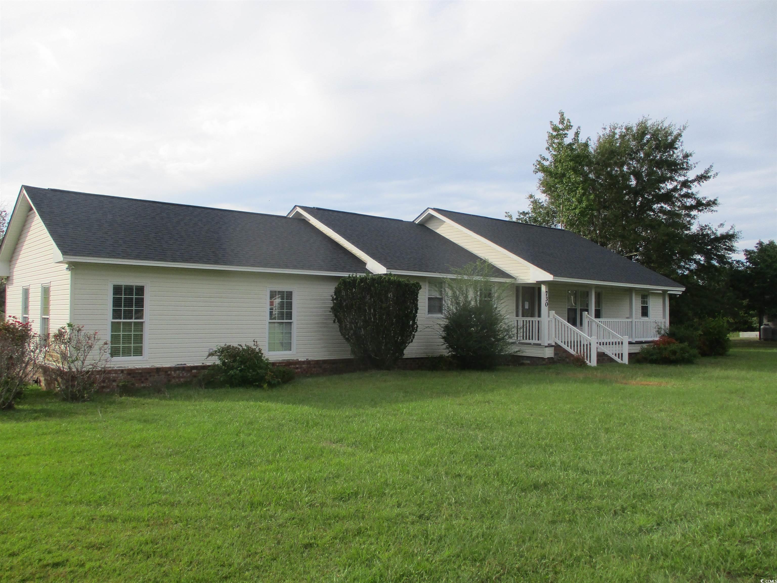 Rear view of house with a lawn and covered porch
