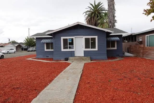 a front view of house with yard and trees in the background