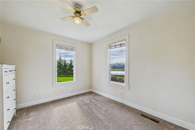an empty room with windows and a ceiling fan