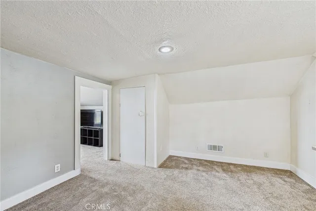 a bedroom with a large bed a flat tv screen and a dresser