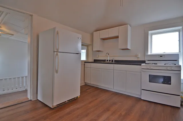 a kitchen with stainless steel appliances white cabinets and wooden floor