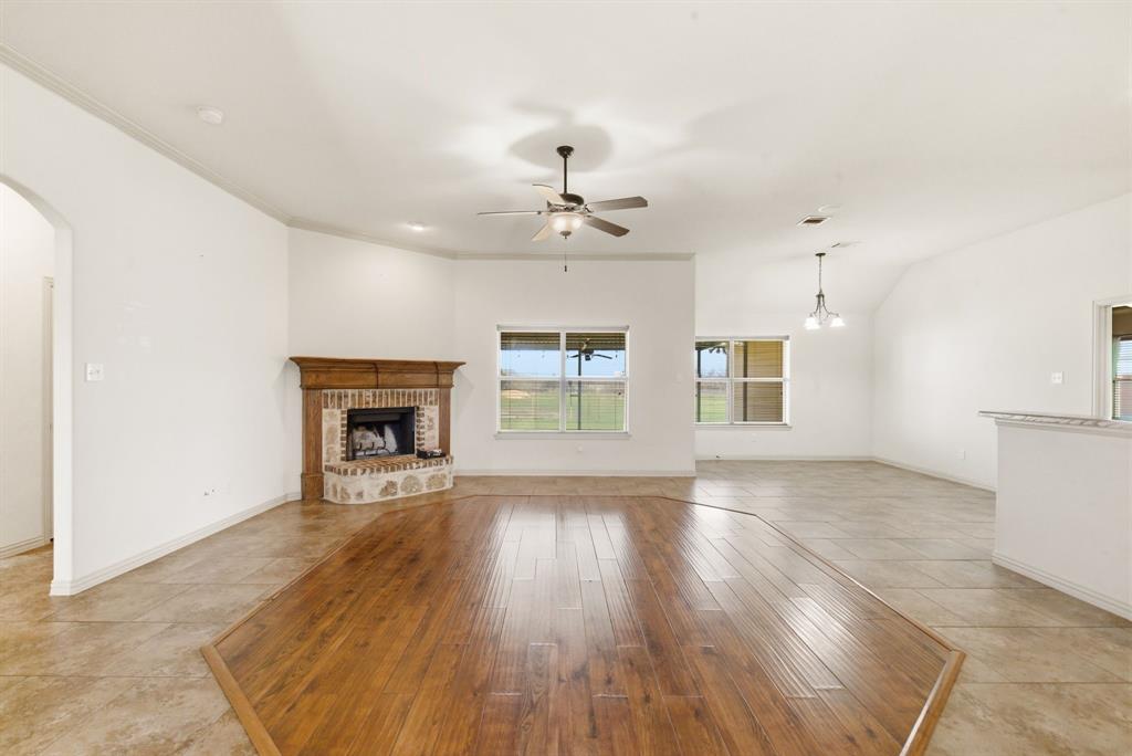 119 Cooperstown Drive Springtown, TX 76082 - Photo 4 of 33 an empty room with wooden floor fireplace and windows