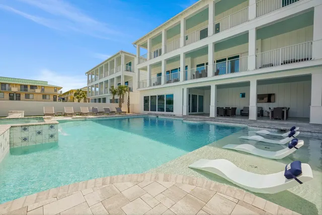 a view of a swimming pool with a bench and cars parked