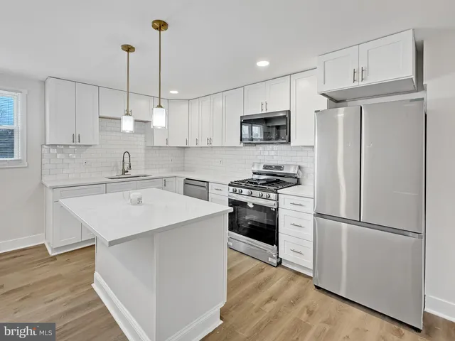 a kitchen with stainless steel appliances kitchen island a refrigerator sink and microwave