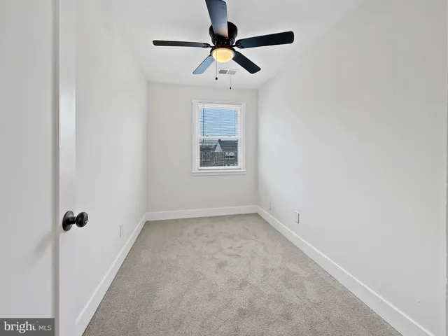 an empty room with a window and a fan
