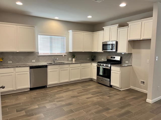 221 Arabian Colt Drive Georgetown, TX 78626 - Photo 5 of 36 a kitchen with granite countertop white cabinets and white appliances