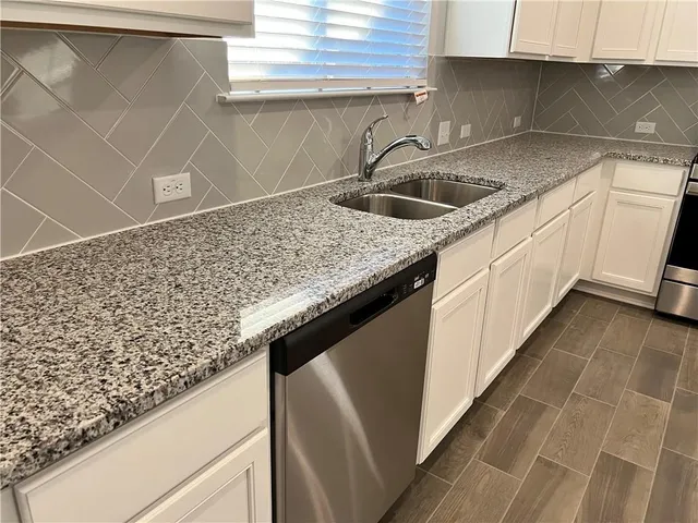 a kitchen with granite countertop a stove top oven sink and cabinets