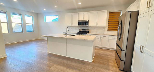 a kitchen with white cabinets and wooden floor