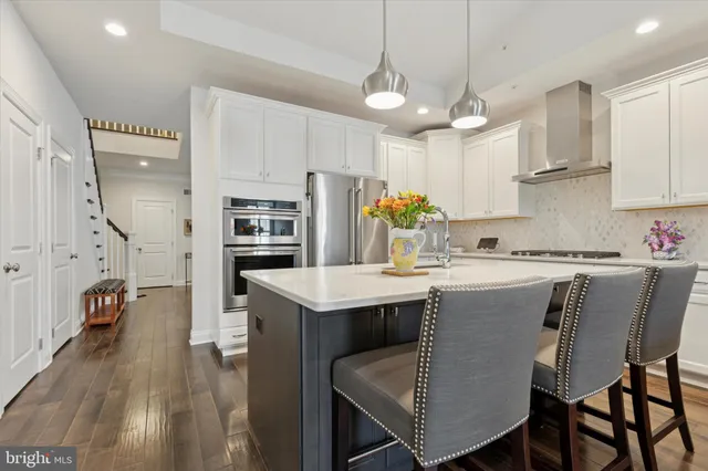 a kitchen with stainless steel appliances granite countertop a table chairs refrigerator and microwave