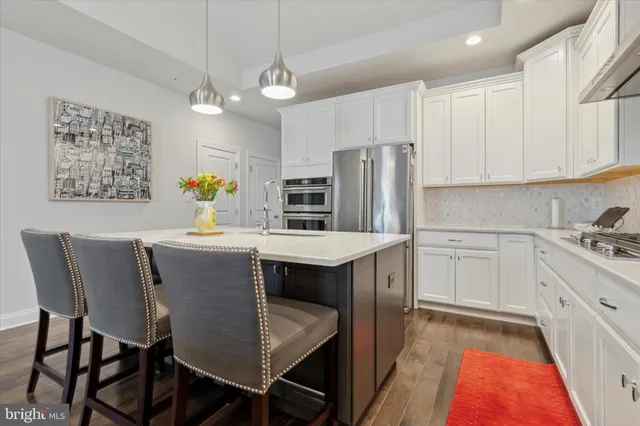 a kitchen with stainless steel appliances kitchen island granite countertop a table chairs and a refrigerator