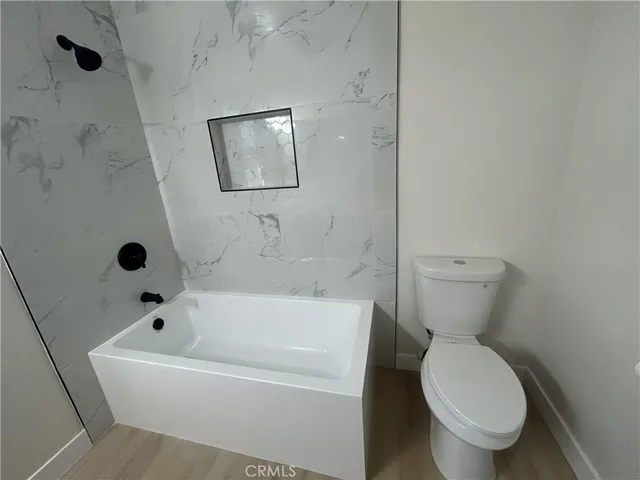 a white toilet sitting next to a tub