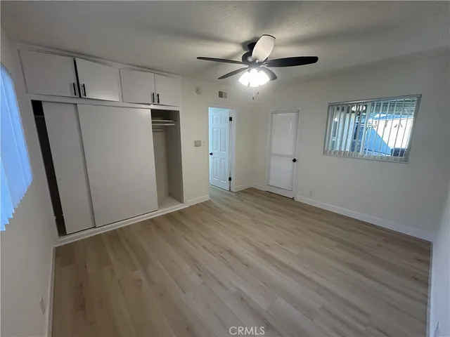 an empty room with wooden floor closet and windows