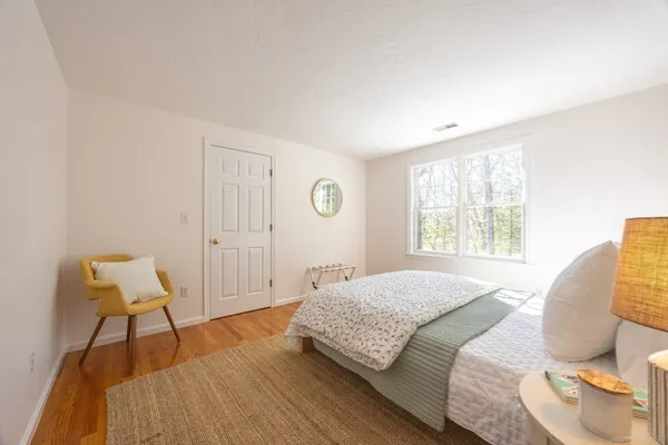 a bedroom with a bed and a chair with the wooden floor