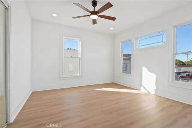 a view of an empty room with window and wooden floor