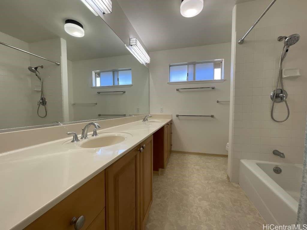 94-1027 Halekapio Street Waipahu, HI 96797 - Photo 12 of 13 a bathroom with a double vanity sink a mirror and a bathtub