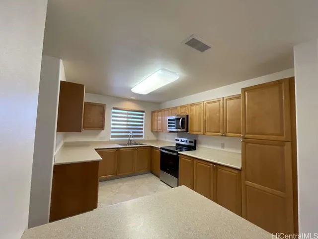 a kitchen with stainless steel appliances a sink a stove a refrigerator cabinets and a window