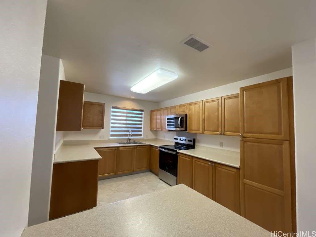 94-1027 Halekapio Street Waipahu, HI 96797 - Photo 4 of 13 a kitchen with stainless steel appliances a sink a stove a refrigerator cabinets and a window
