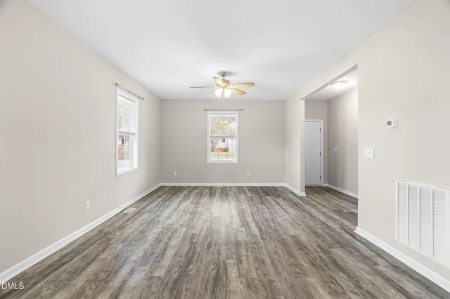 an empty room with wooden floor and windows