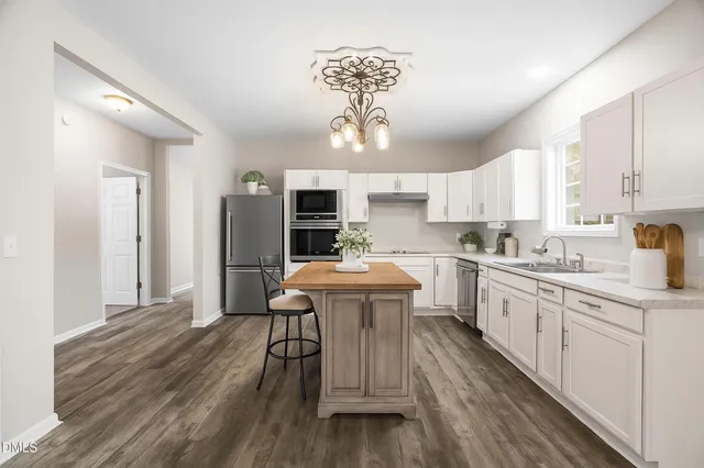 a kitchen with stainless steel appliances a dining table chairs a sink dishwasher window and cabinets