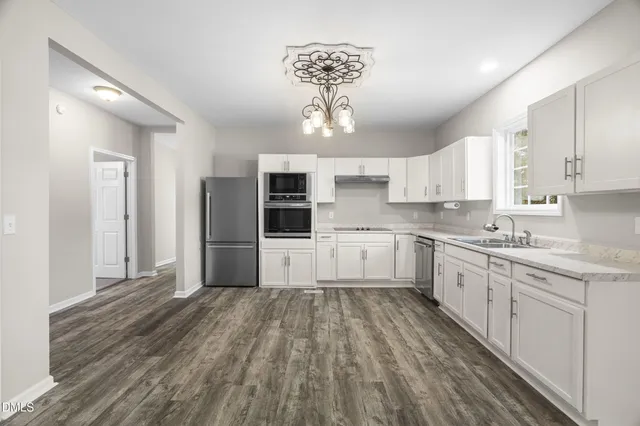 a kitchen with granite countertop a refrigerator and white cabinets