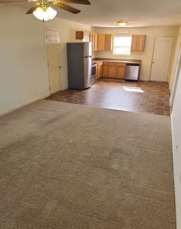 a view of kitchen and empty room with wooden floor
