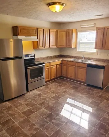 a kitchen with granite countertop a stove a sink and a refrigerator