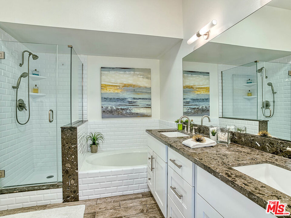 1133 9th Street, Unit 304 Santa Monica, CA 90403 - Photo 12 of 25 a bathroom with a granite countertop tub a double vanity sink and a mirror