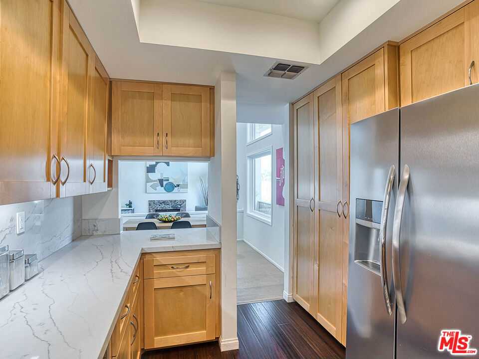 1133 9th Street, Unit 304 Santa Monica, CA 90403 - Photo 6 of 25 a kitchen with stainless steel appliances granite countertop a refrigerator a stove and a sink with wooden floor