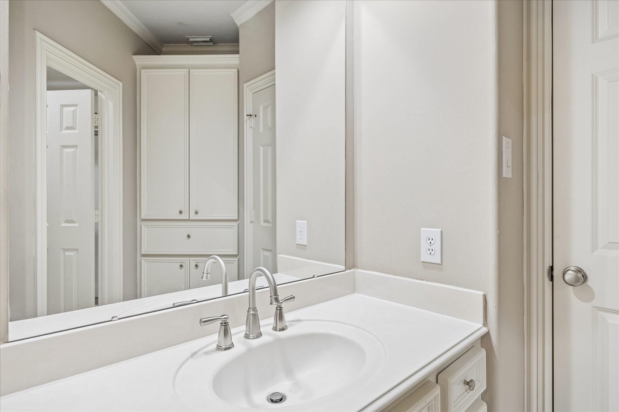 35 North Regent Oak Spring, TX 77381 - Photo 29 of 43 One of the two private vanity areas within the Jack-and-Jill bathroom, featuring a spacious countertop, large mirror, generous storage cabinetry, and an additional built-in linen cabinet. This thoughtful layout allows each adjoining bedroom to enjoy its own dedicated sink and vanity space while sharing the bathing area, offering both convenience and privacy for family members or guests.