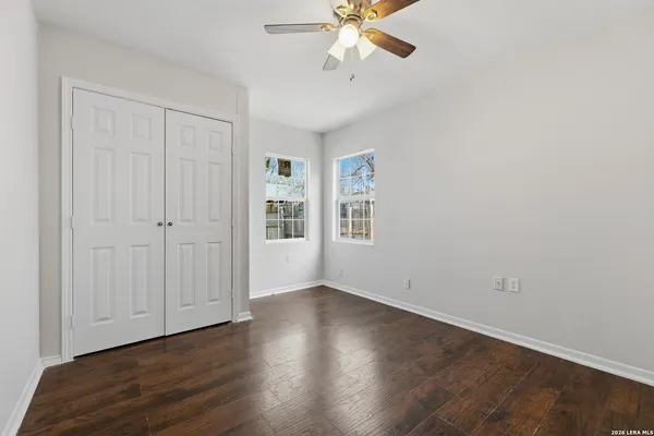 an empty room with wooden floor closet and windows