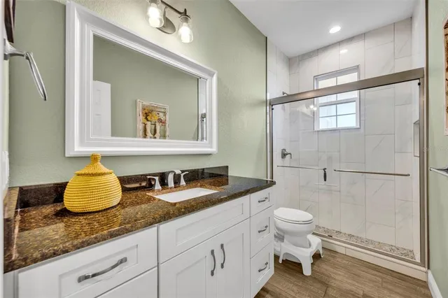 a bathroom with a granite countertop sink mirror vanity and toilet