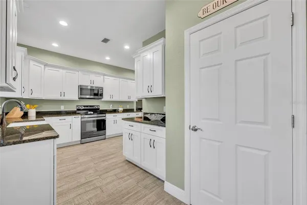 a kitchen with granite countertop white cabinets and stainless steel appliances