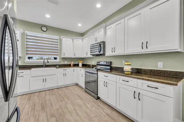 a kitchen with granite countertop white cabinets and white appliances