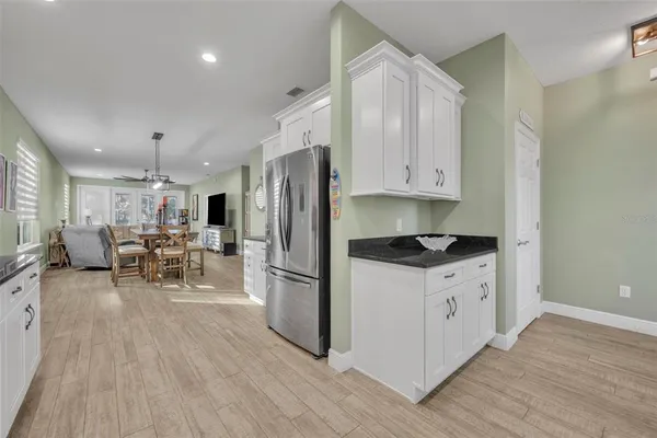 a kitchen with stainless steel appliances kitchen island granite countertop a refrigerator a stove a sink and a dining table with wooden floor