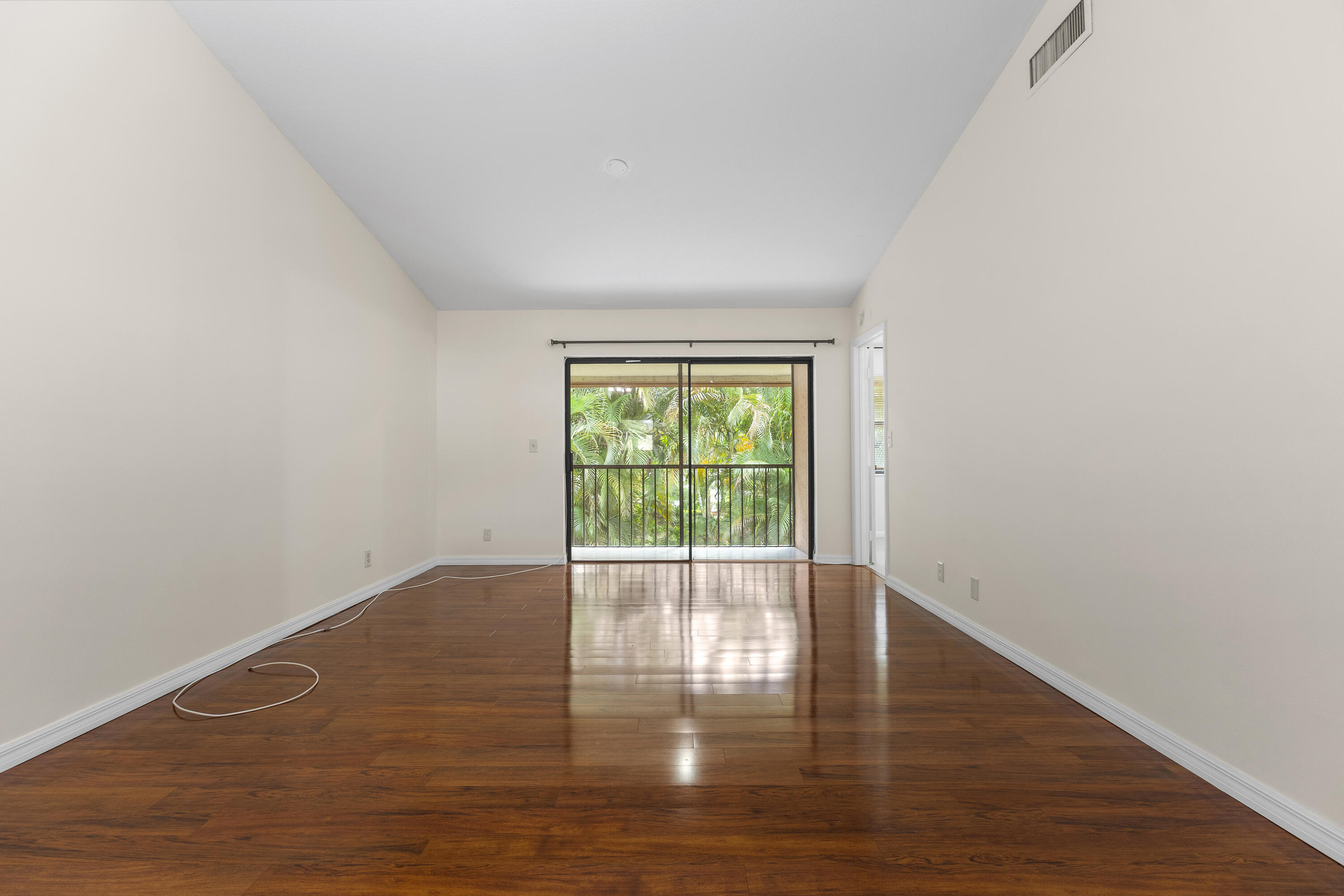 22076 Palms Way, Unit 202 Boca Raton, FL 33433 - Photo 9 of 35 a view of an empty room with wooden floor and a window
