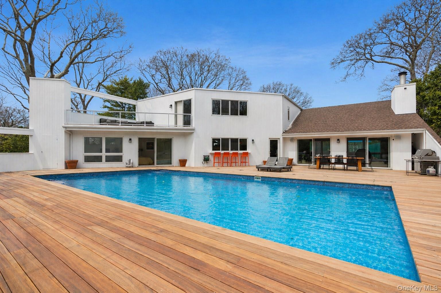 2 Acorn Path Quogue, NY 11959 - Photo 1 of 16 Expansive wood-finish pool deck featuring an in-ground gunite heated swimming pool