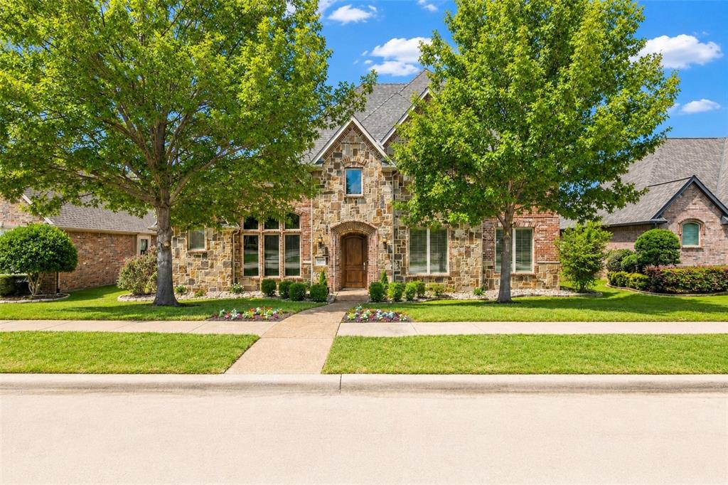 967 East Bethel School Road Coppell, TX 75019 - Photo 1 of 39 Stone and brick exterior featuring an arched entryway with a wood door, multiple gabled rooflines, and a manicured lawn with mature trees