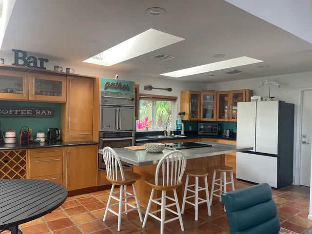 a kitchen with stainless steel appliances granite countertop a dining table chairs cabinets and a refrigerator