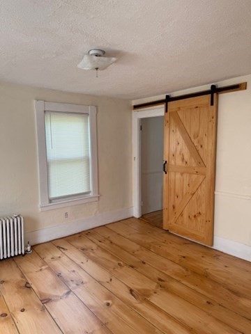 113 West Main Street, Unit 113 Ayer, MA 01432 - Photo 3 of 17 a view of an empty room with wooden floor and a window