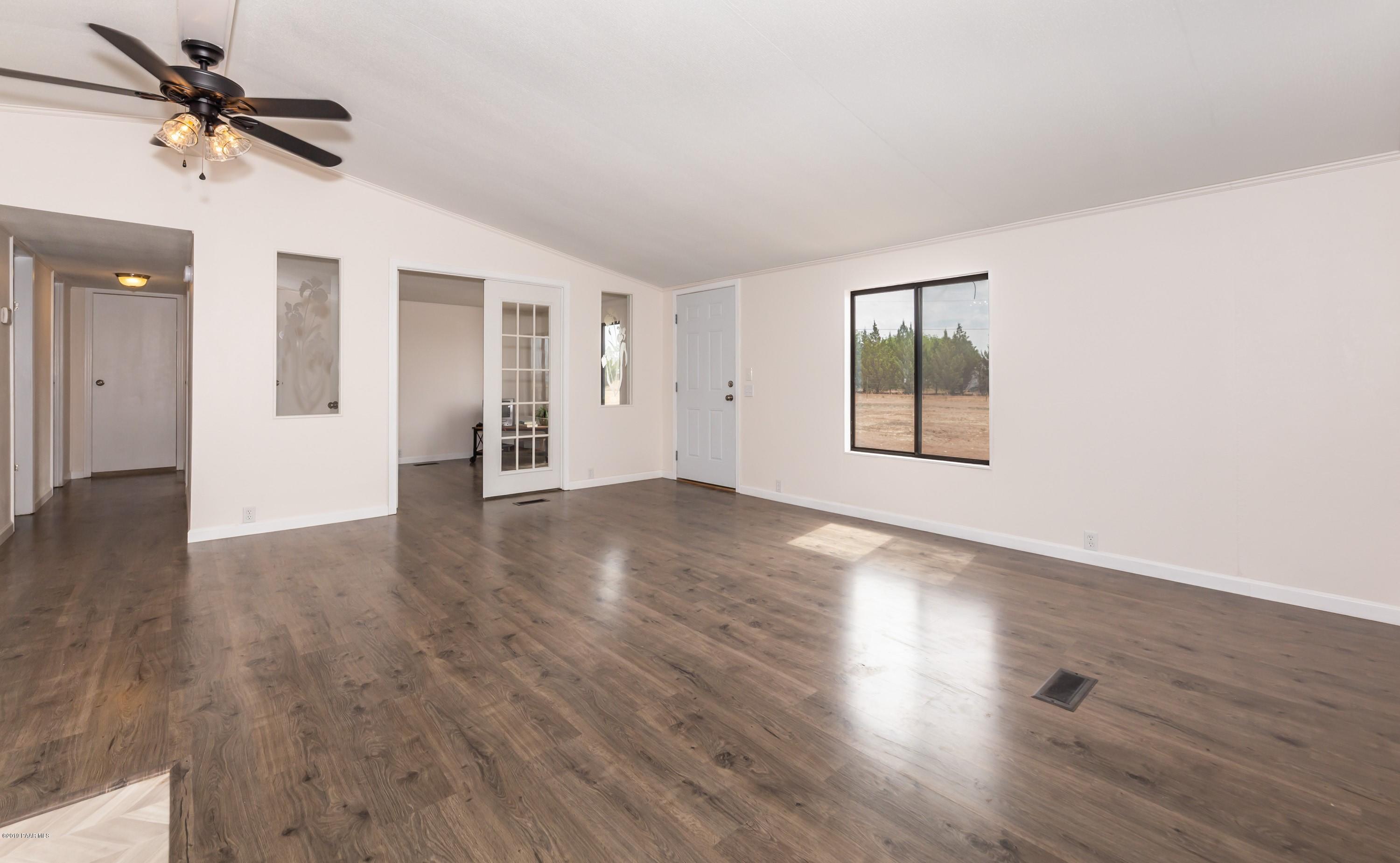25156 North Stump Road Paulden, AZ 86334 - Photo 3 of 17 an empty room with wooden floor chandelier fan and windows