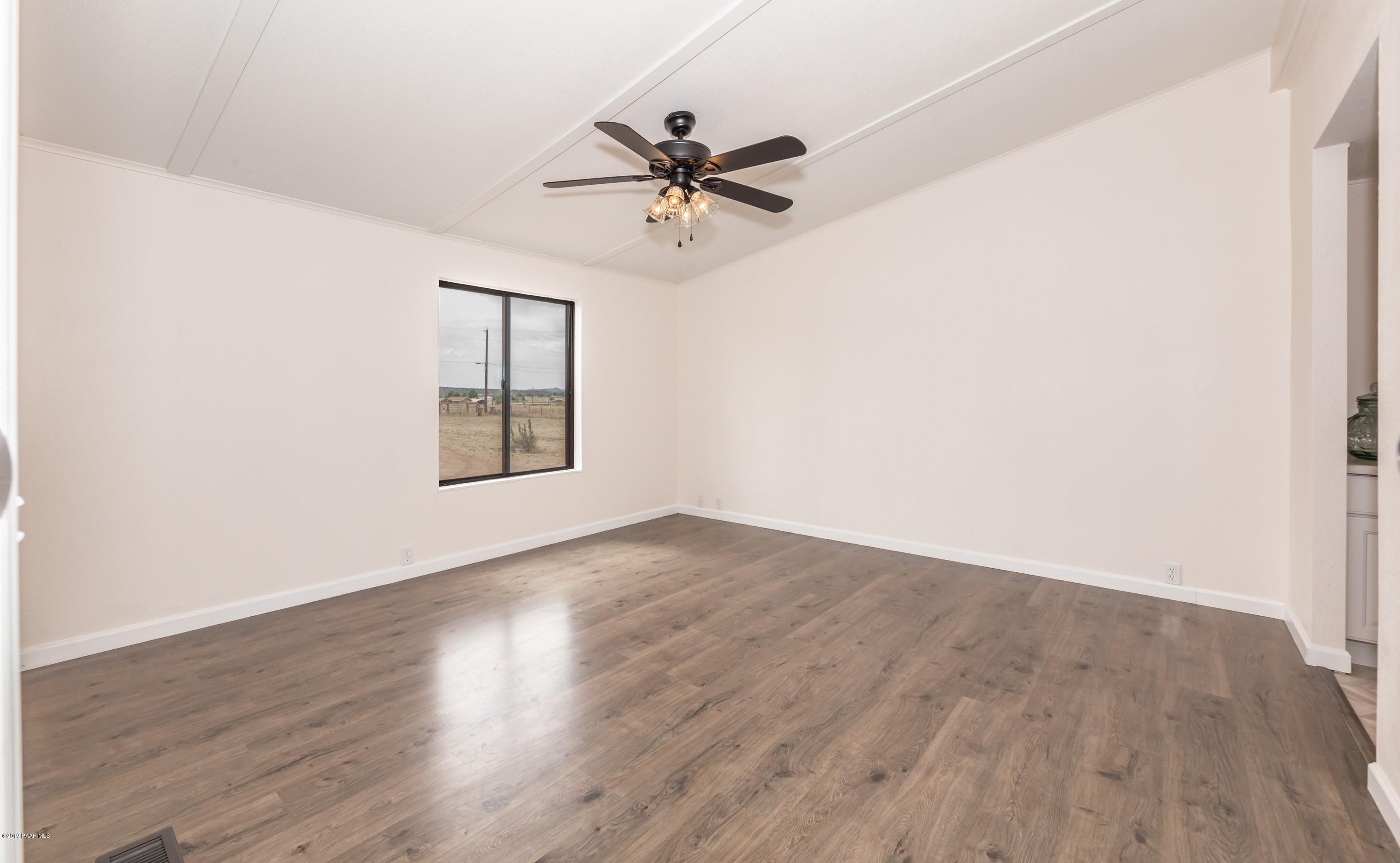 25156 North Stump Road Paulden, AZ 86334 - Photo 8 of 17 an empty room with wooden floor a ceiling fan and windows