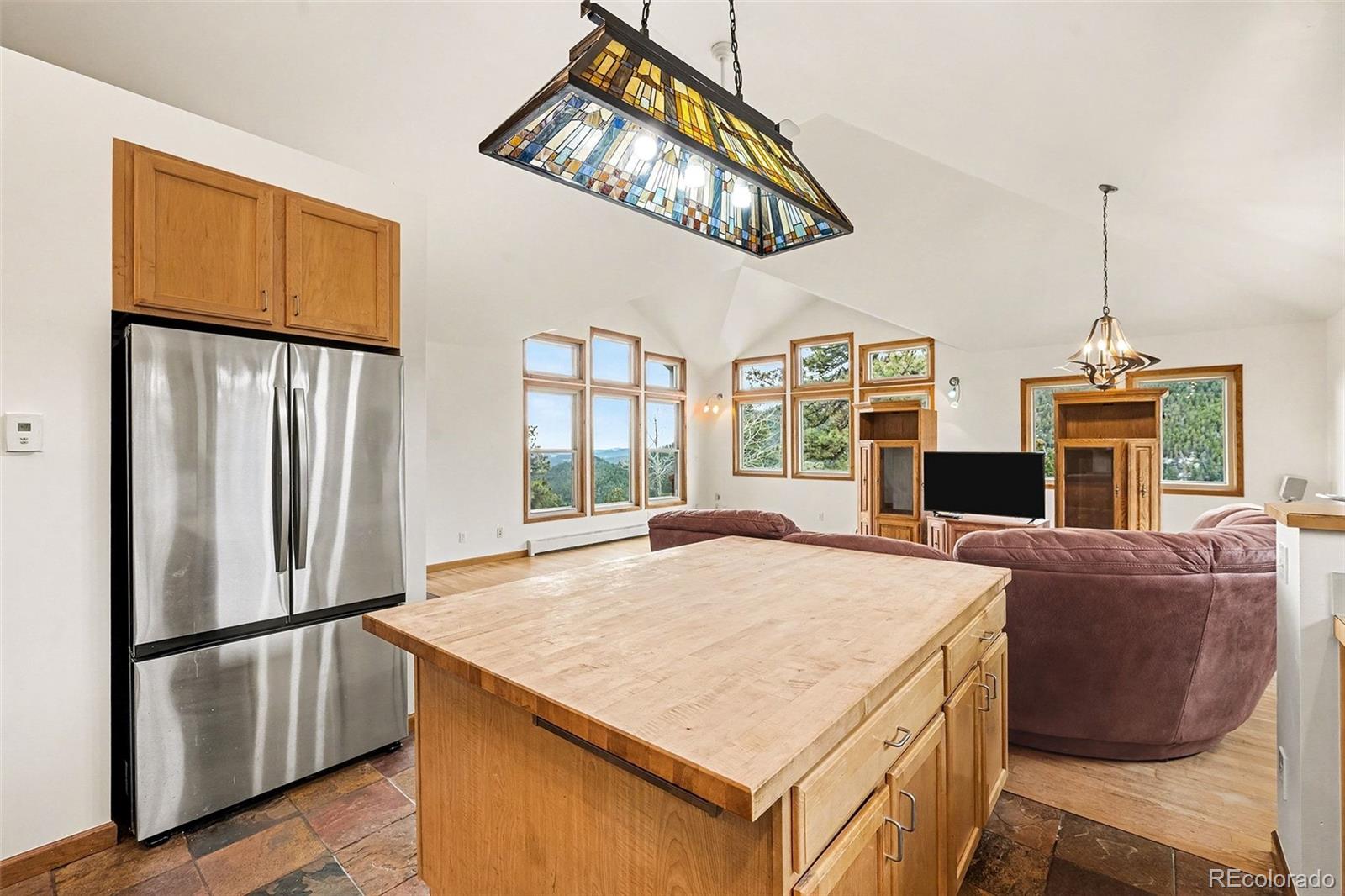 6094 Pyrenees Trail Golden, CO 80403 - Photo 5 of 24 a kitchen with stainless steel appliances granite countertop a refrigerator a sink dishwasher a stove and a dining table with wooden floor