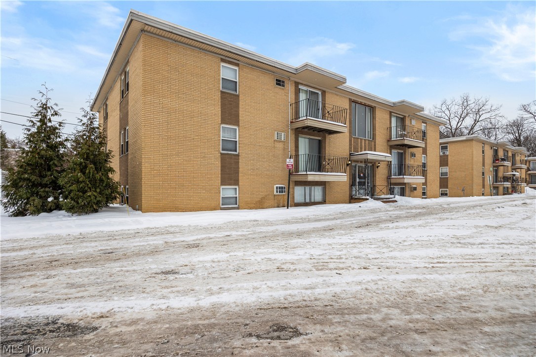 Snow covered building featuring a view of apartment building / complex