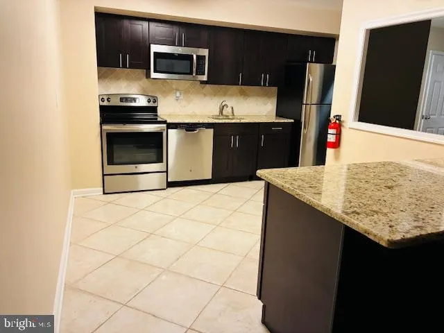 a kitchen with stainless steel appliances a sink a stove a microwave a counter top and cabinets