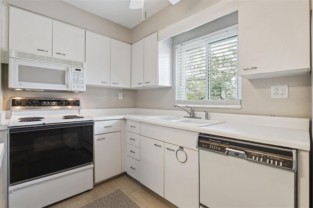 525 South Conway Road, Unit 202 Orlando, FL 32807 - Photo 12 of 34 a kitchen with granite countertop white cabinets and white appliances