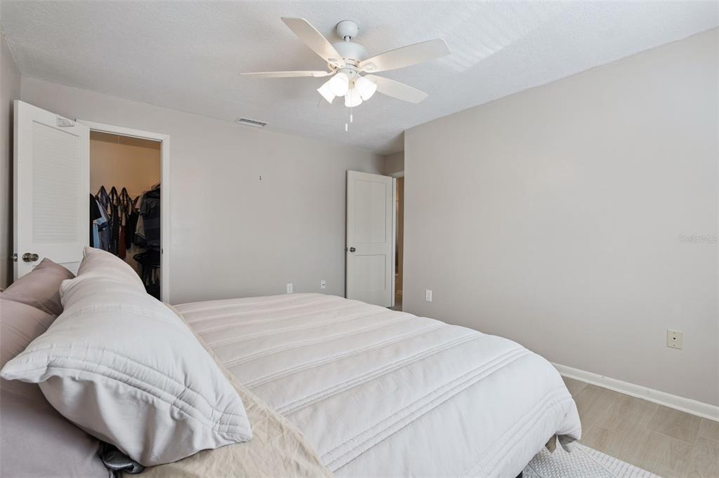 525 South Conway Road, Unit 202 Orlando, FL 32807 - Photo 15 of 34 a bedroom with a white bed and ceiling fan