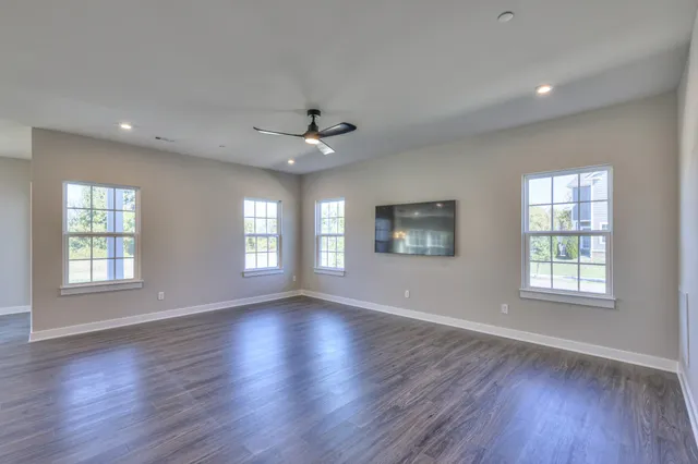 a large kitchen with stainless steel appliances granite countertop a large counter top a wooden floors and a large window