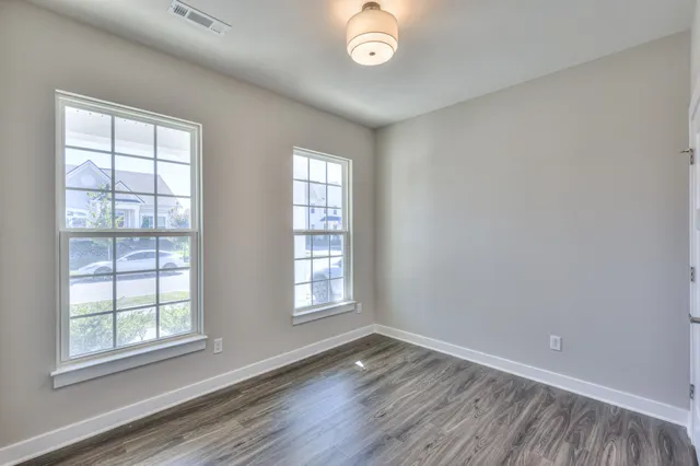 a view of an empty room with wooden floor and closet
