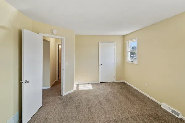 a view of an empty room with closet and a window