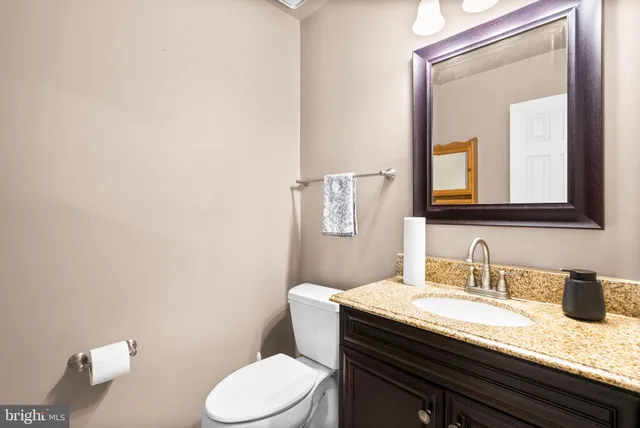 a bathroom with a granite countertop toilet sink and mirror